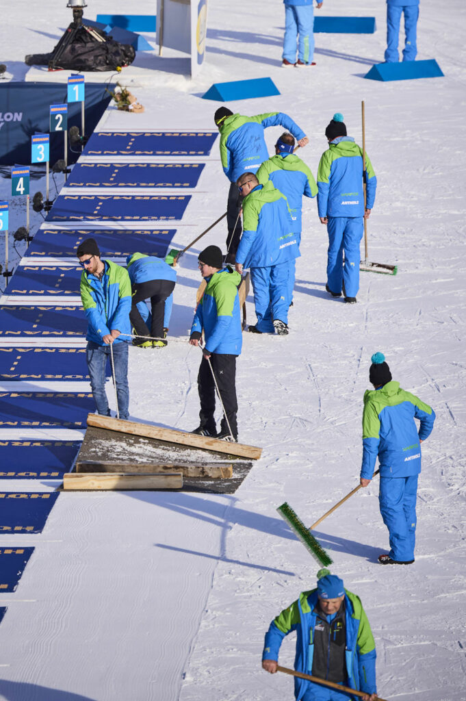 Freiwillige Helfer präparieren den Schnee in der Olympic Arena in Antholz